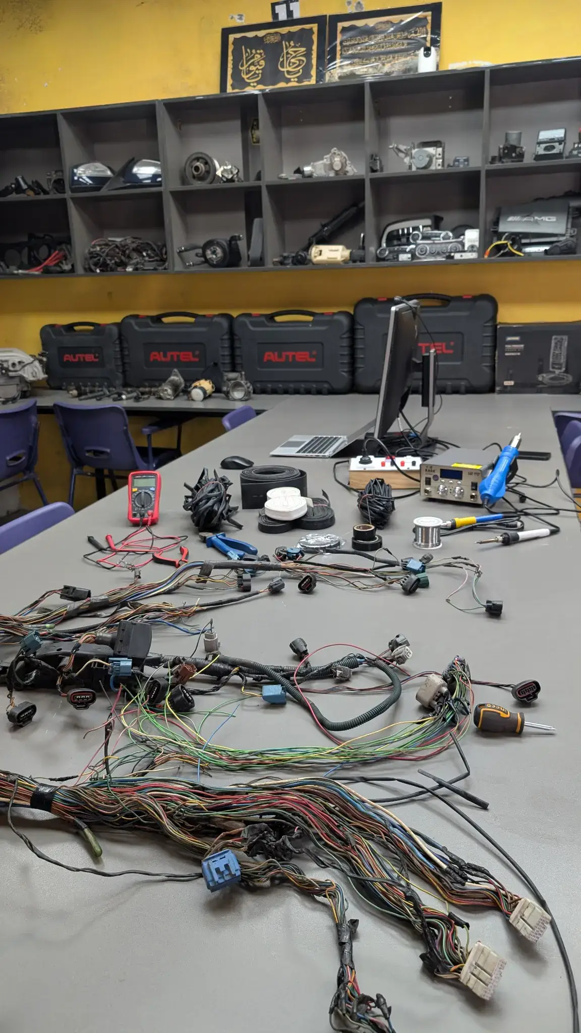 Actual HPR Academy classroom with automotive wiring harnesses, diagnostic equipment, and electronics tools